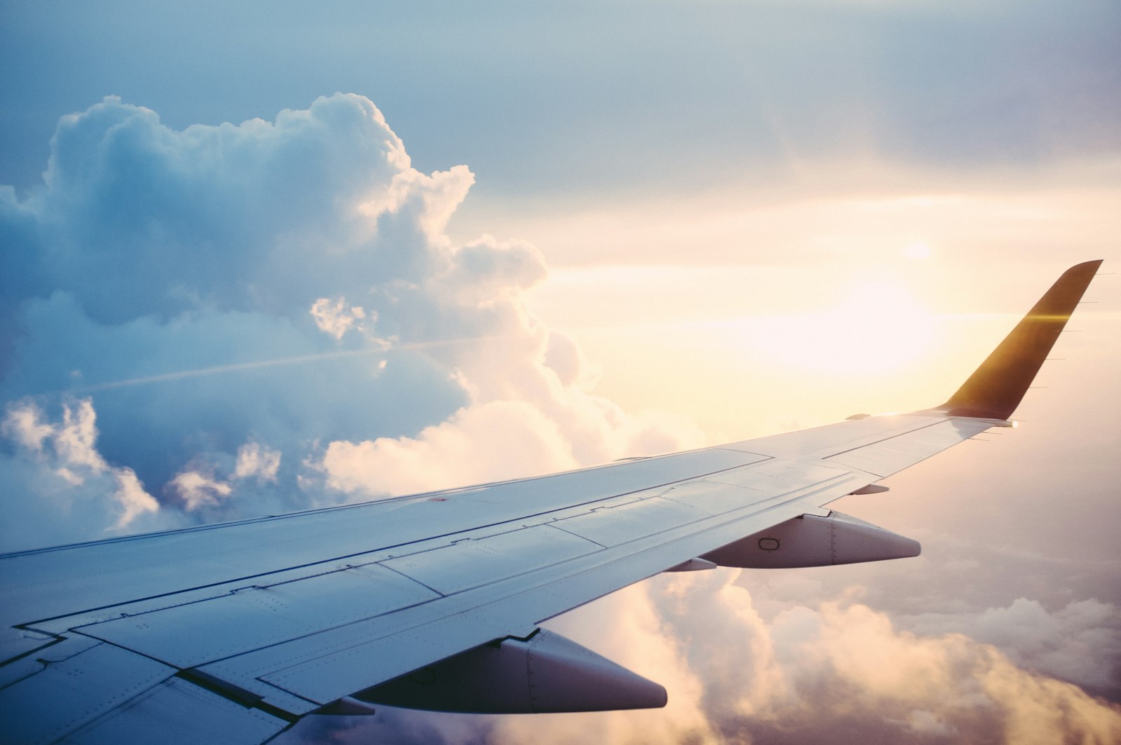Aerial view of an aircraft wing over the ocean at sunset